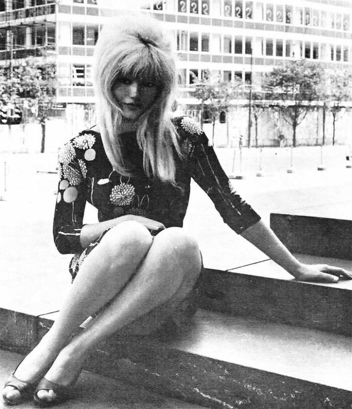 Woman with long hair sitting on outdoor steps, representing people who left a mark in the movie and music industries.