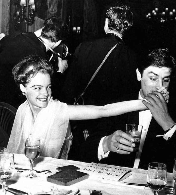 Black and white photo of iconic movie and music industry stars sharing a joyful moment at an elegant event.