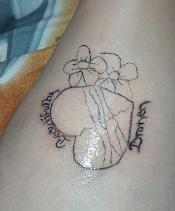 Black ink tattoo on skin featuring a heart with flowers and cursive text, an example of unusual tattoos on bodies.