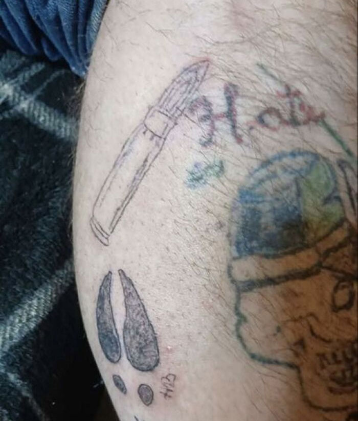 Tattoo of a poorly drawn lipstick, teardrops, and a skull on leg skin, showing unusual permanent body tattoos.