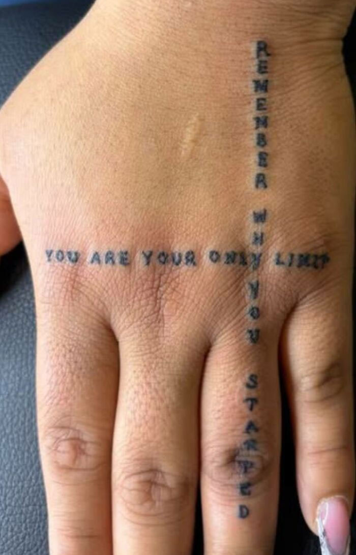 Close-up of hand tattoo with words forming a cross, showcasing one of the 91 tattoos people allowed on their bodies.