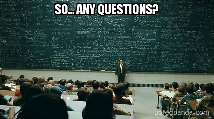 Teacher standing in front of a large, complex chalkboard full of equations, asking if there are any questions.