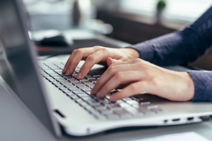 Person typing on a laptop keyboard in an office setting, illustrating unexpected and awkward moments at work.