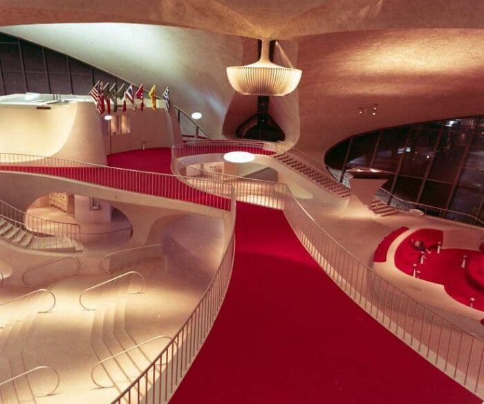 Futuristic interior with flowing architectural curves and red carpet, showcasing a beautiful yet unnerving liminal space.