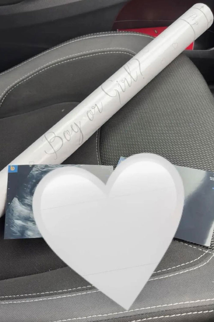 Ultrasound photos and gender reveal scroll placed on a car seat, related to woman's outrageous baby doll lie.