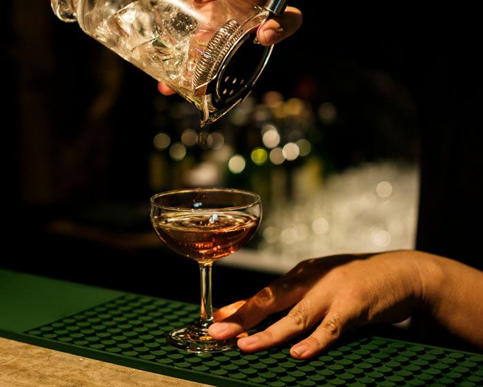 Bartender pouring a cocktail into a glass, illustrating a story about worst employees bosses have dealt with.