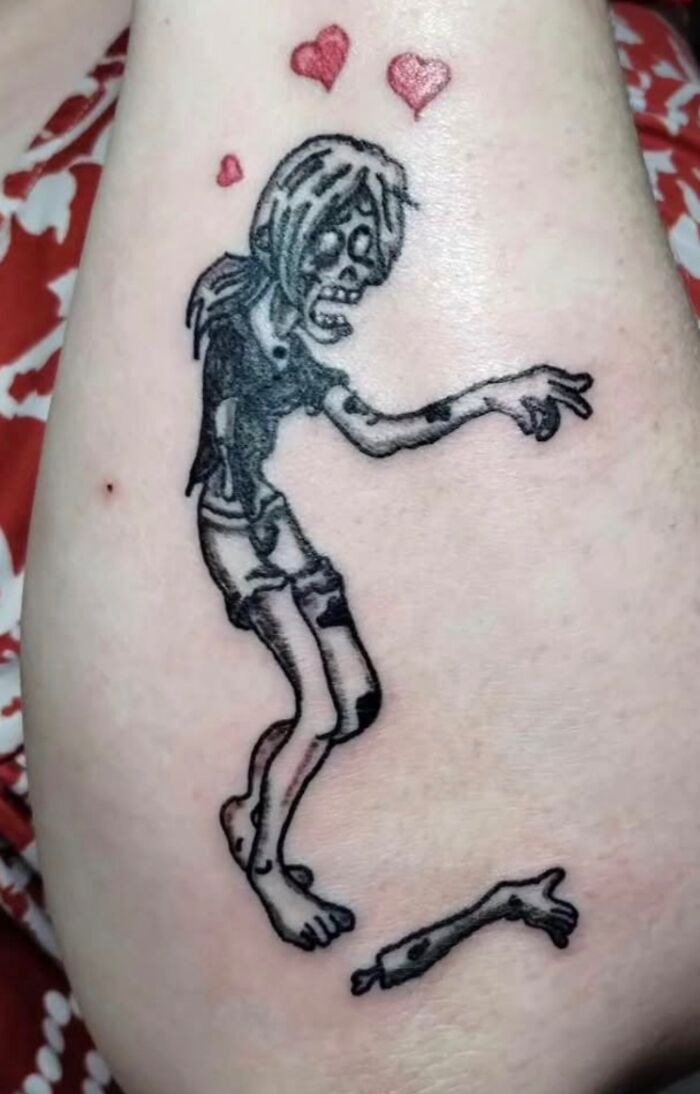 Zombie tattoo with broken arm and hearts, an unusual design from 91 tattoos you wouldn’t believe allowed on bodies.