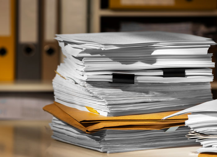 Stack of paperwork and files representing plastic surgeons documenting unnecessary surgeries performed.