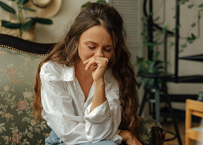 Young woman sitting on a floral sofa looking distressed, illustrating common mental health myths and misconceptions.
