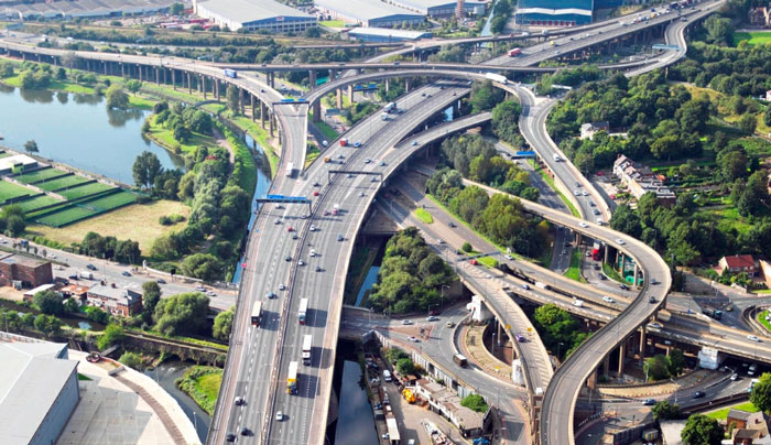 A complex highway interchange surrounded by greenery and industrial buildings, illustrating places people wouldn’t revisit.