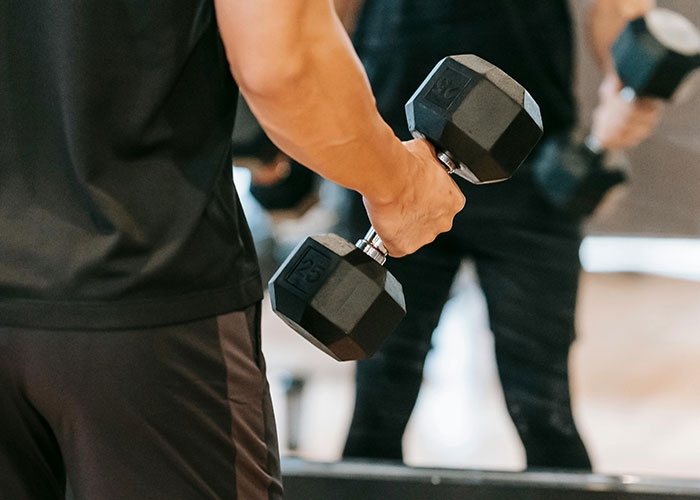 Man holding a dumbbell in a gym setting, focusing on strength training and fitness activities.