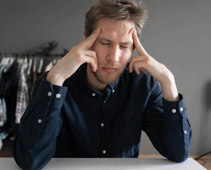 Young man appears clueless and stressed, holding his head while his wife suffers from a high fever at home.