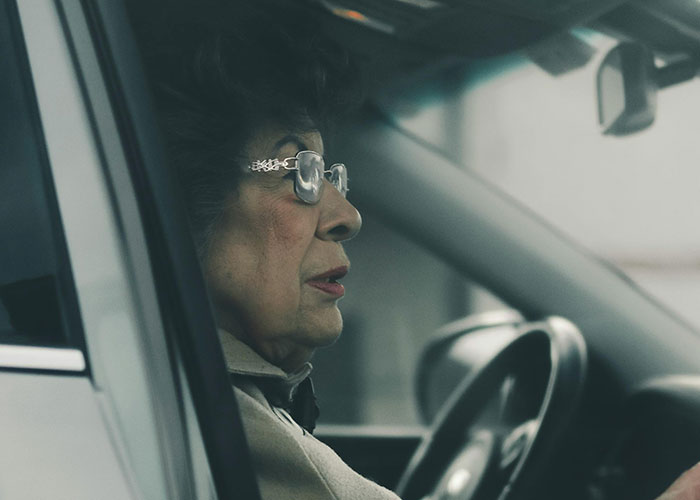 Older woman sitting in a car, looking concerned, illustrating moms sharing a time their kid embarrassed them badly.