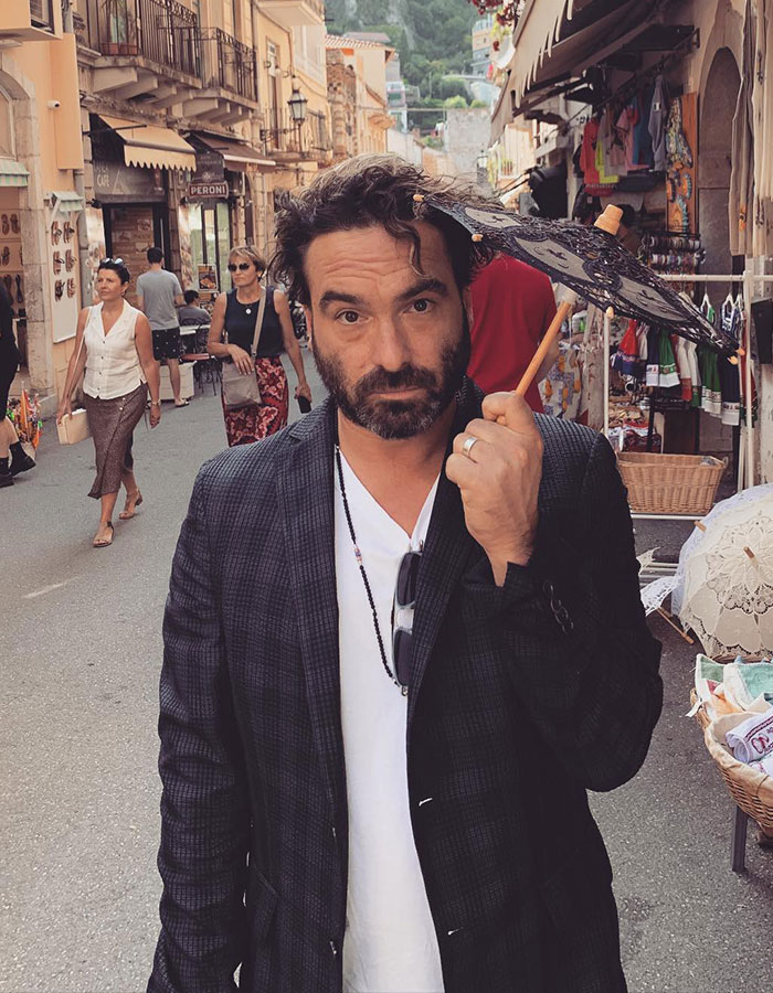 Man holding a small decorative umbrella in a busy street, illustrating famous men who are shorter than fans imagined.