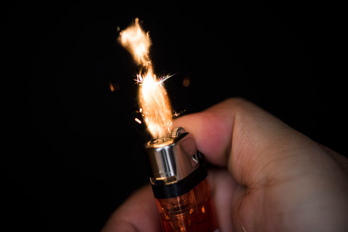 Close-up of hand igniting a lighter with sparks, illustrating worst crimes involving fire in hometowns.