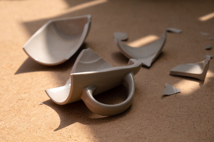 Broken ceramic mug pieces scattered on the floor, illustrating challenges during moving and packing boxes efficiently.