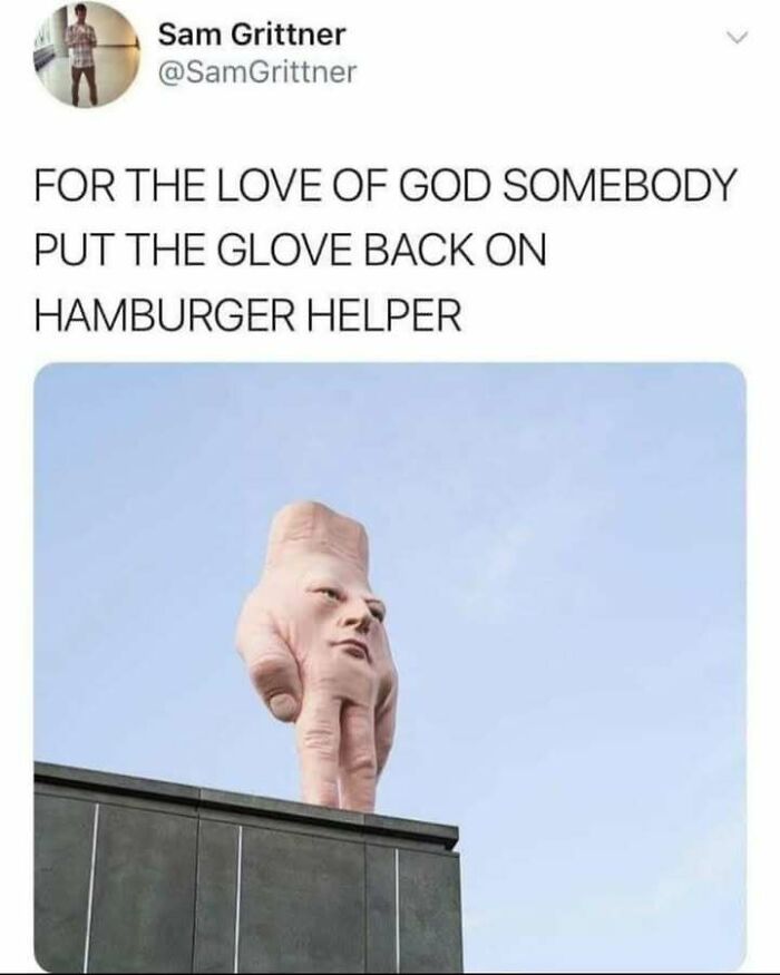 Surreal image of a giant hand with a human face standing on a rooftop, a confusing image that gets weirder the longer you look.