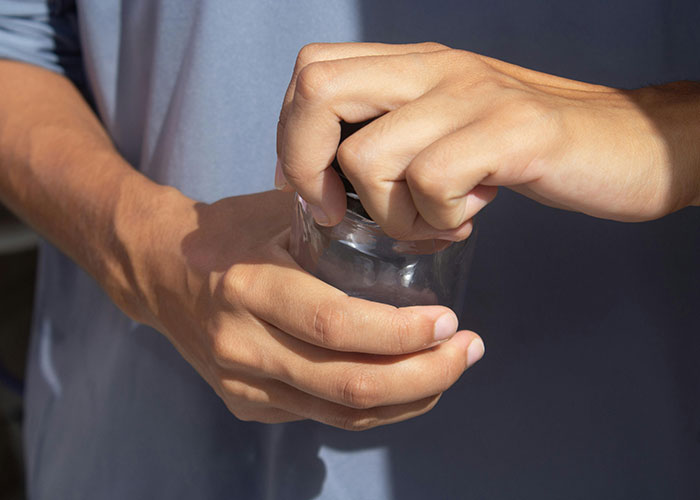 Person using a life hack to open a tight jar lid, demonstrating practical and accidental life hacks still in use today.
