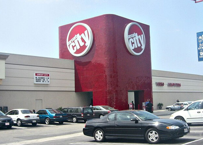Parking lot outside a Circuit City store with several cars, illustrating people using loopholes against horrible bosses.