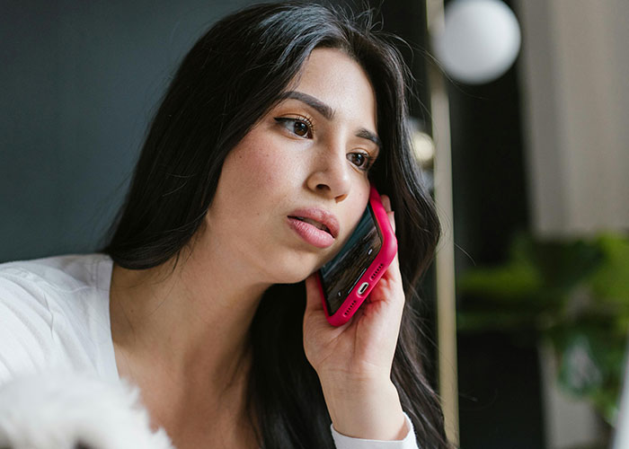 Young woman with long dark hair talking on a smartphone showing a creepy expression that left men horrified