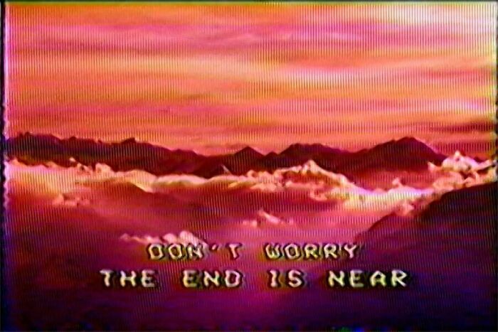 Glitchy sunset image with pixelated text saying the end is near, a confusing visual where things get weirder the longer you look.
