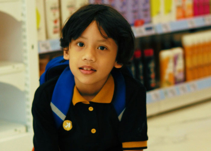 Young boy with backpack in a store aisle, illustrating kids embarrassing moms in everyday moments.