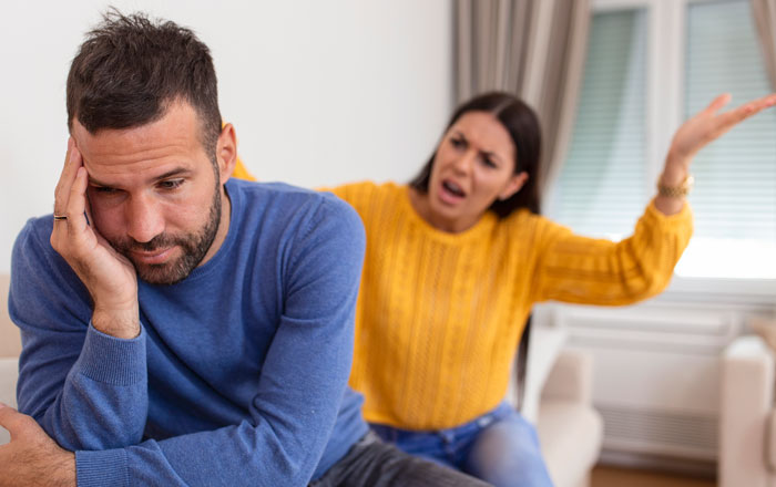 Man looking upset while woman angrily gestures behind him depicting a cruel person encounter.