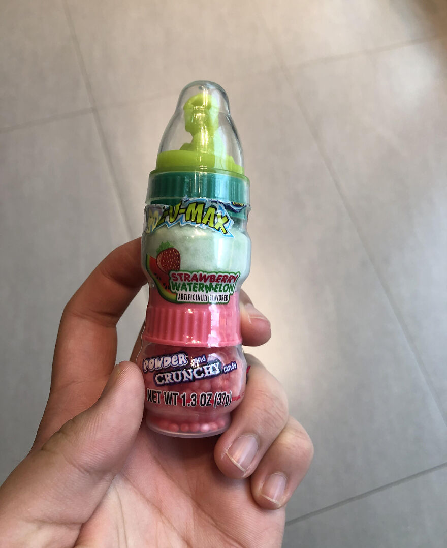 Hand holding a strawberry watermelon flavored Halloween candy with powder and crunchy candy inside, popular in 2025.