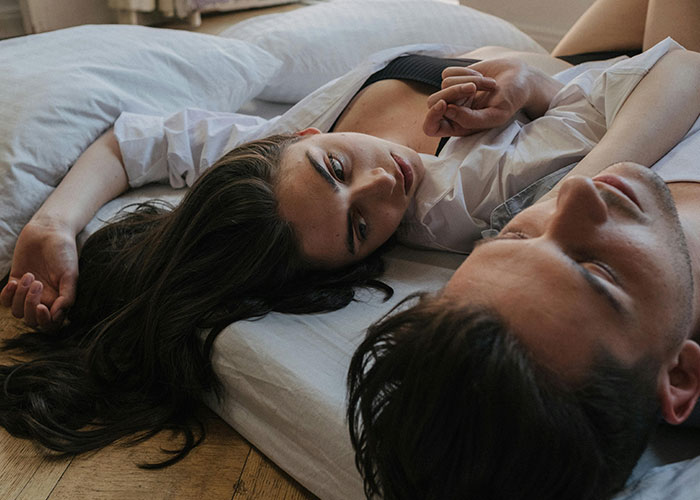 Woman and man lying down together indoors, capturing creepy things women said or did to men moments.