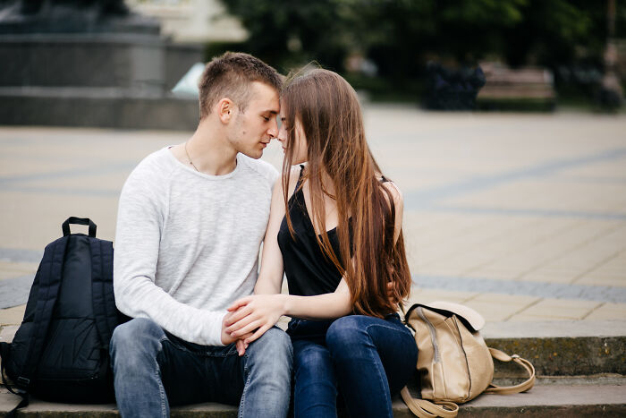 Young couple sitting close on steps outdoors, illustrating social cues misreading in a hilariously painful moment.