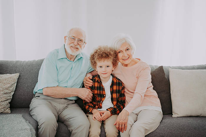 Elderly grandparents sitting on a couch with a young boy, symbolizing family support after bio mom abandonment. Elderly grandparents sitting on a couch with a young boy, symbolizing family support after bio mom abandonment.