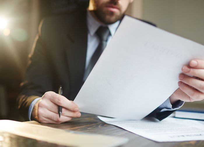 Man in suit reviewing documents at desk, symbolizing cruel person evaluation for horrifyingly cruel person stories.