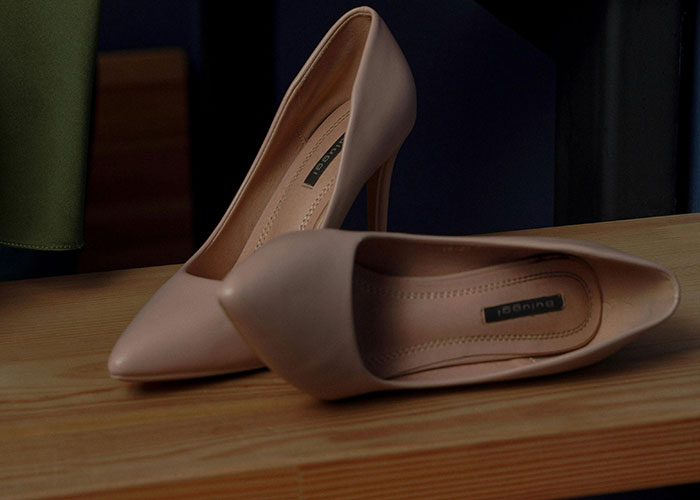 Beige high heels on a wooden surface symbolizing creative loopholes used against horrible bosses in workplace challenges.