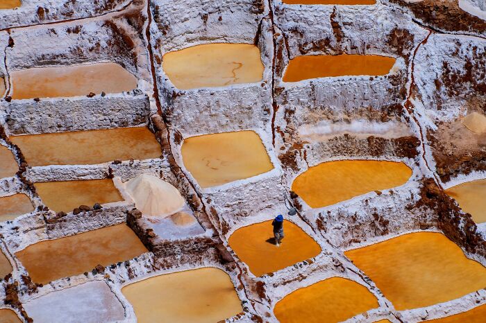 Award-winning photo from the 1839 Awards showing a person walking through vibrant orange and yellow salt terraces.