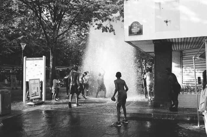 Children playing in water spray at park, featured among award-winning photos in the 2025 Photographer Of The Year contest.