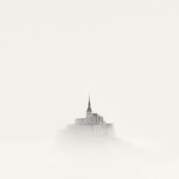 Faded medieval castle rising through thick mist, showcasing artistry of 2025 Photographer Of The Year award-winning photos.