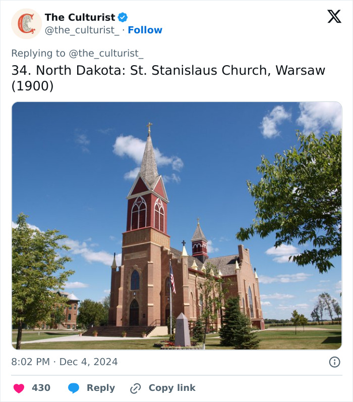 St. Stanislaus Church in North Dakota with tall steeple under blue sky, a beautiful striking church from the US.