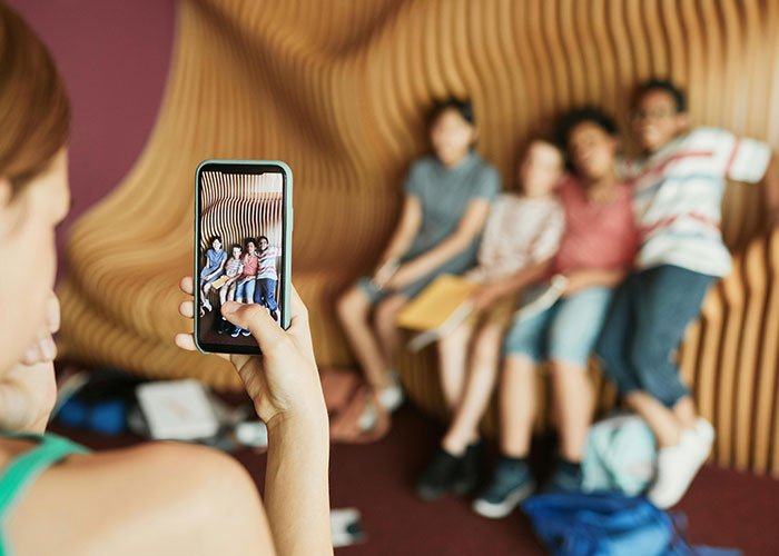 Person capturing group photo on smartphone, demonstrating everyday life hacks discovered accidentally and still used today