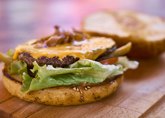 Close-up of a cheeseburger with lettuce on a wooden surface, illustrating creative loopholes against horrible bosses.