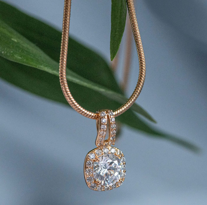 Close-up of a gold necklace with a diamond pendant, highlighting intricate jewelry craftsmanship and sparkling stones.