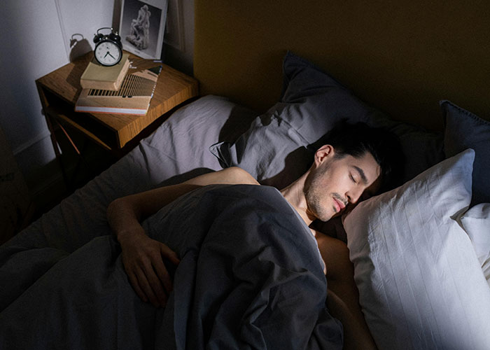 Man sleeping uneasily in bed at night, representing creepy things women said or did that left men horrified.