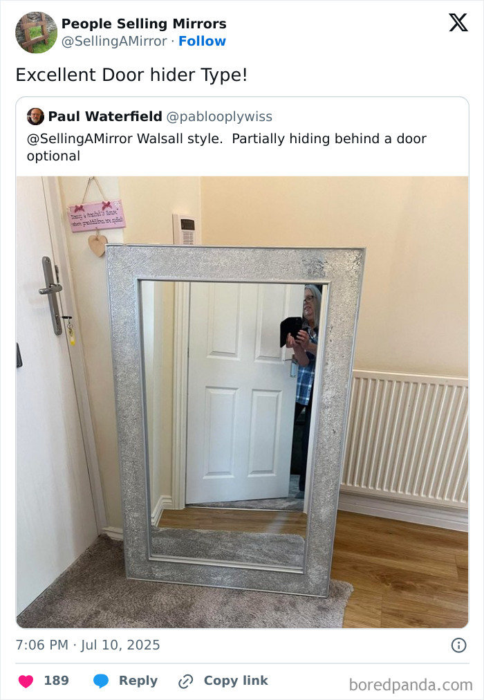 Large silver-framed mirror leaning against a wall, reflecting a person partially hidden behind a door in a home setting.