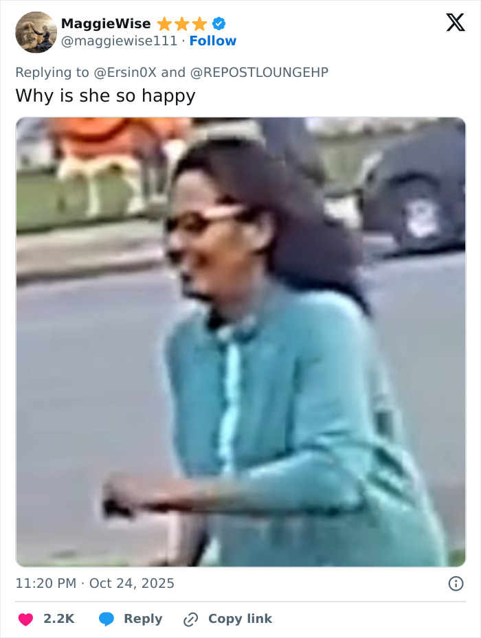 Woman caught attacking neighbor's Halloween witches outdoors, smiling and wearing glasses and a teal long-sleeve shirt.