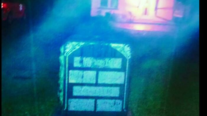 Grainy nighttime photo of a tombstone faintly illuminated, creating a creepy atmosphere that feels unsettling and eerie.