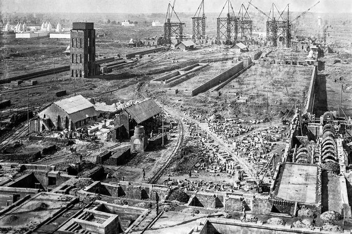 Black and white photo showing an industrial site with cranes and buildings in a world capital long before modern times.