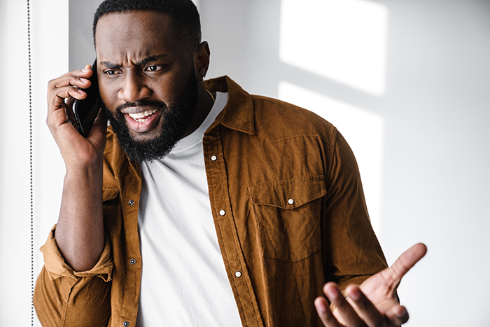 Man in brown shirt talking on phone with surprised expression, reacting to $50K guitar deal and refusal to sell back. Man in brown shirt talking on phone with surprised expression, reacting to $50K guitar deal and refusal to sell back.