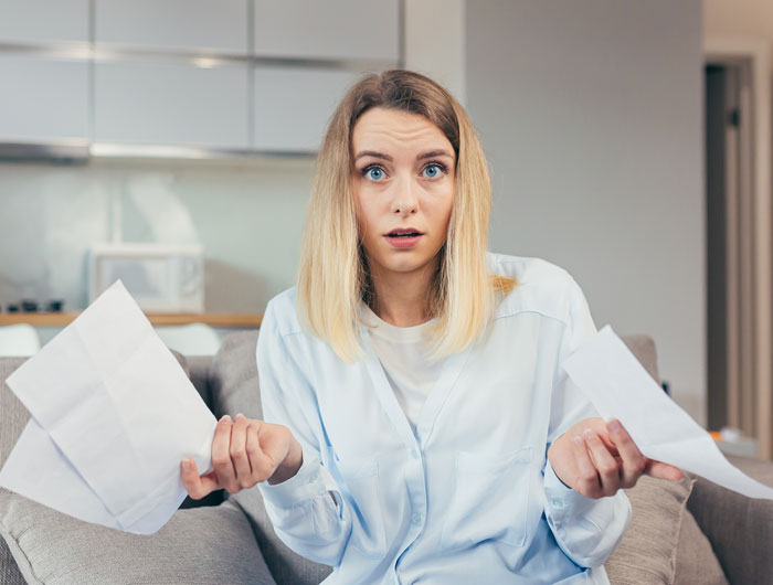 Woman in a living room looking confused and holding papers, depicting drama from a fake adoption family plan.