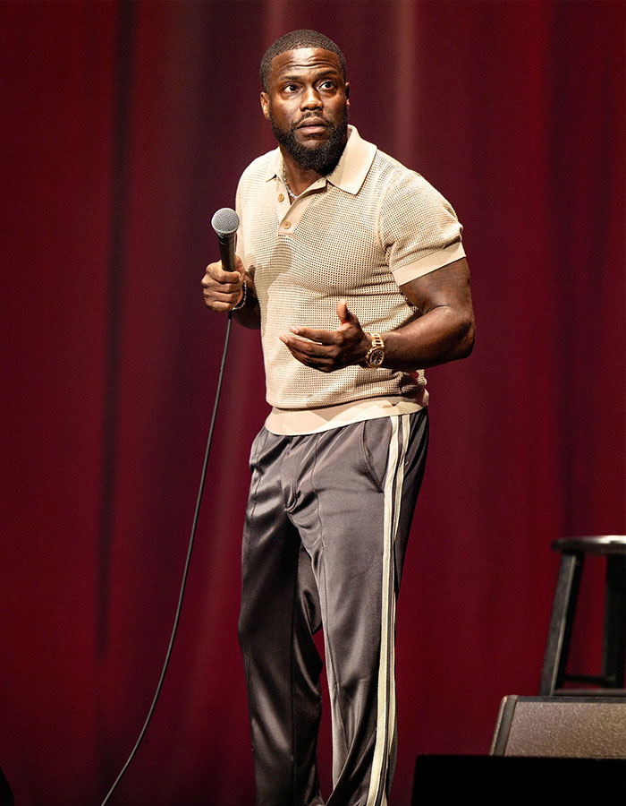 Comedian performing on stage with microphone, illustrating famous men who are much shorter than fans imagined.