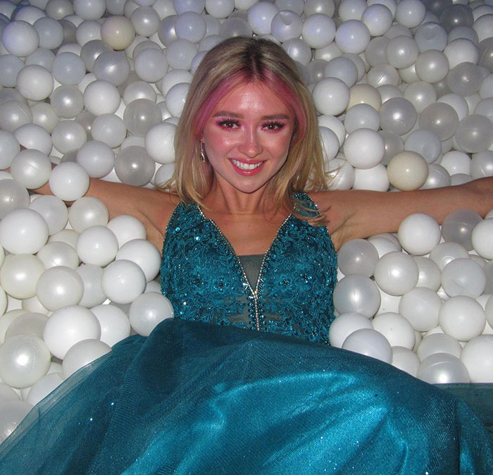 Young woman in a blue dress smiling while sitting in a pool filled with white plastic balls, symbolizing refusal of chemo. Young woman in a blue dress smiling while sitting in a pool filled with white plastic balls, symbolizing refusal of chemo.