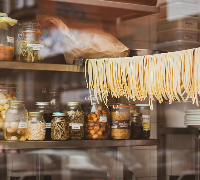 Fresh pasta hanging to dry in an Italian kitchen with jars of ingredients, linked to American tourist and Olive Garden dish request.
